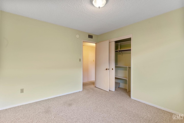 unfurnished bedroom with a textured ceiling, a closet, and light carpet