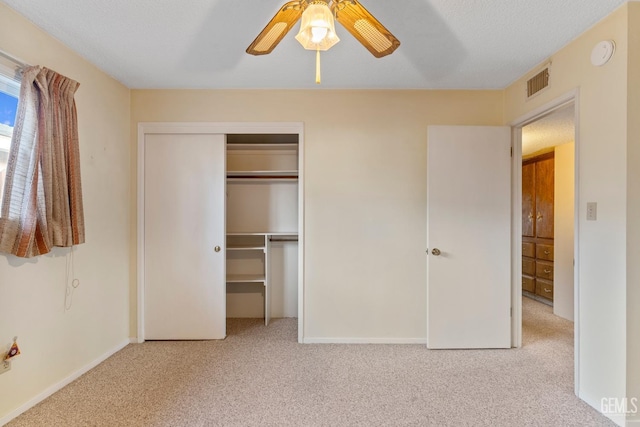 unfurnished bedroom featuring light colored carpet, ceiling fan, and a closet