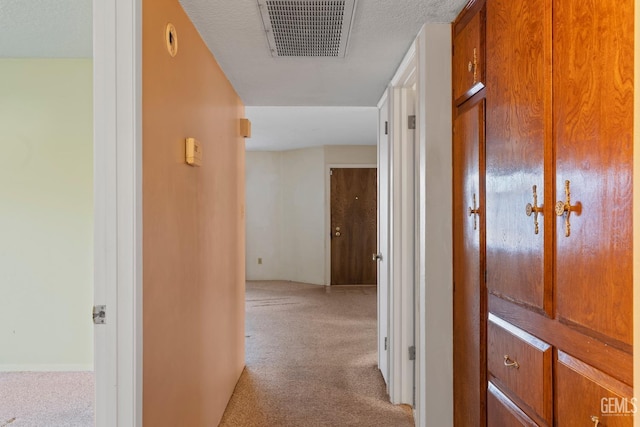 hallway featuring a textured ceiling and light colored carpet