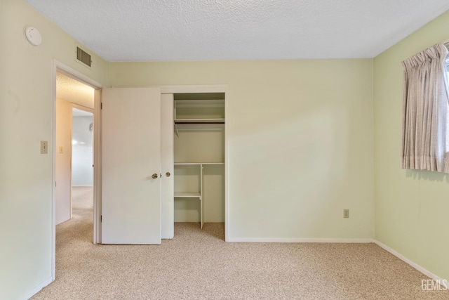 unfurnished bedroom featuring light colored carpet, a closet, and a textured ceiling