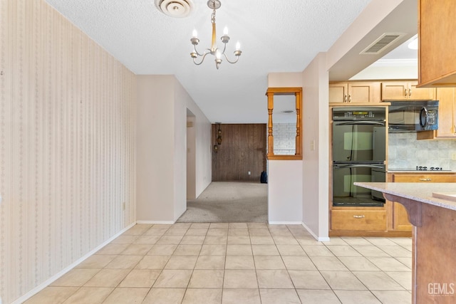 kitchen featuring decorative light fixtures, a textured ceiling, black appliances, and a notable chandelier