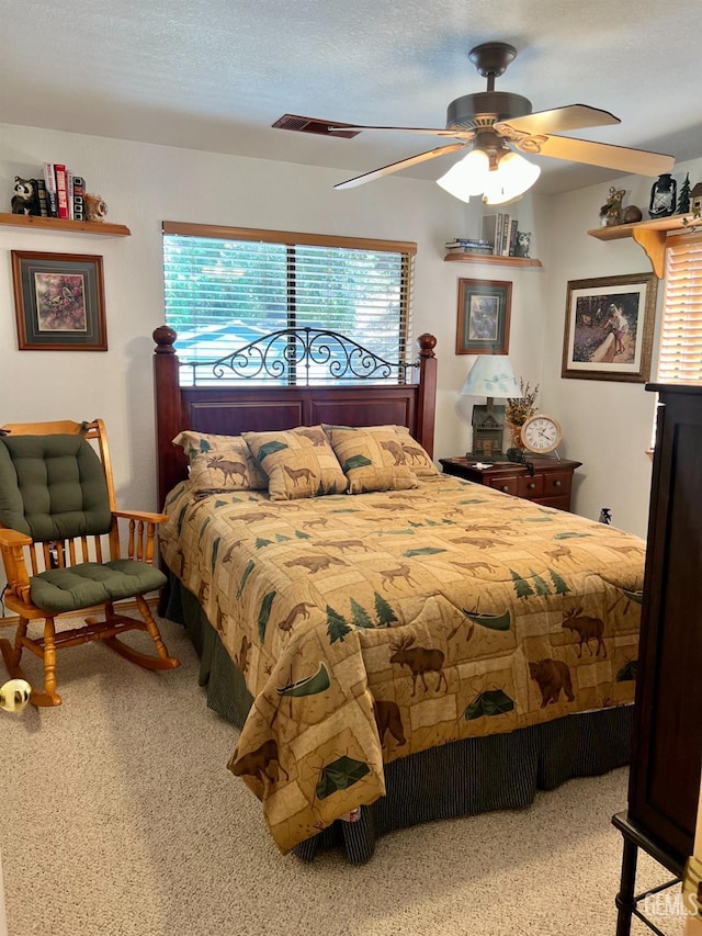 carpeted bedroom with ceiling fan and a textured ceiling