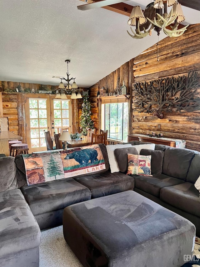 living room featuring rustic walls, a wealth of natural light, lofted ceiling, and an inviting chandelier