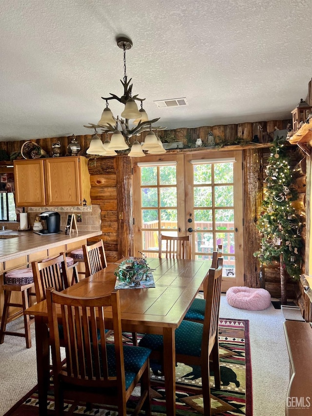 dining room featuring light carpet, french doors, a textured ceiling, and rustic walls