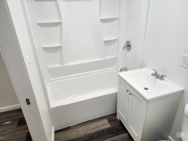 bathroom featuring toilet, washtub / shower combination, wood finished floors, and vanity