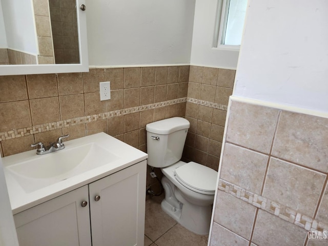 bathroom with tile walls, vanity, toilet, and tile patterned floors