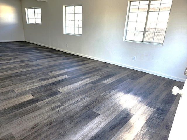 spare room featuring dark wood-style flooring and baseboards