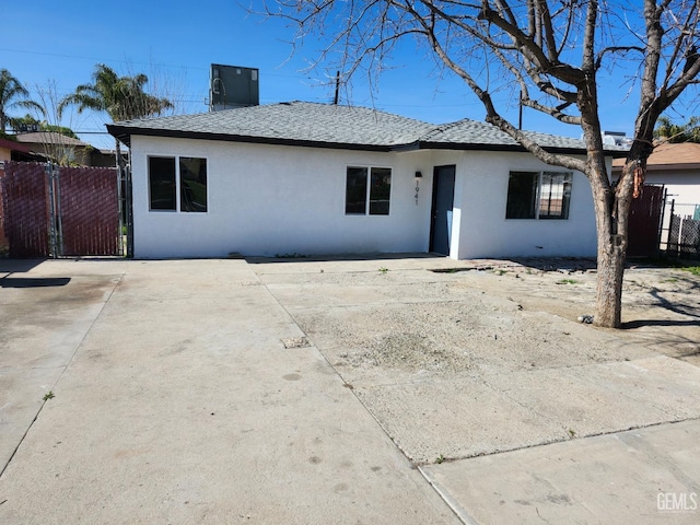 rear view of house featuring a patio area, a shingled roof, fence, and stucco siding