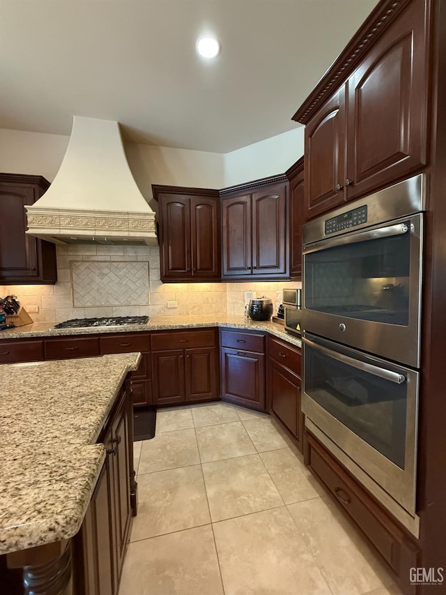 2410 Exton St, Bakersfield, CA 93311 - kitchen featuring custom exhaust hood, appliances with stainless steel finishes, tasteful backsplash, light stone counters, and light tile patterned floors