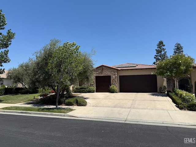 2410 Exton St, Bakersfield, CA 93311 - view of front of house with a garage, roof mounted solar panels, a tiled roof, driveway, and stucco siding