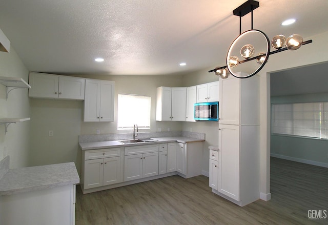 118 W 20th Ave, Delano, CA 93215 - kitchen featuring stainless steel microwave, a sink, light wood-type flooring, white cabinets, and light countertops