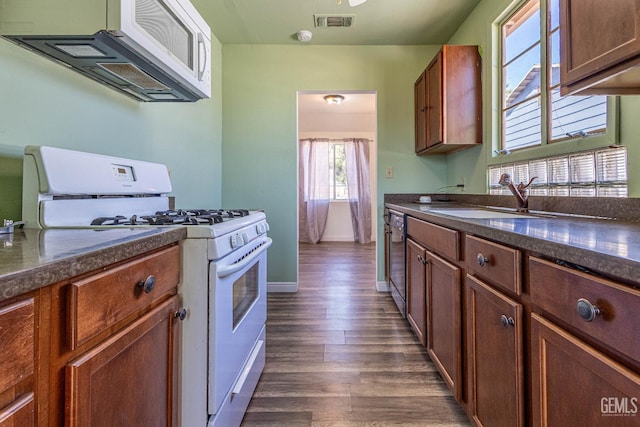 kitchen featuring white range with gas stovetop, black dishwasher, dark hardwood / wood-style floors, and sink