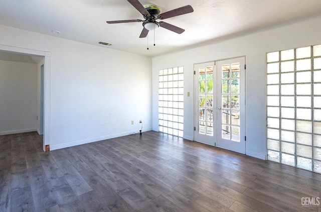 empty room with french doors, ceiling fan, and dark wood-type flooring