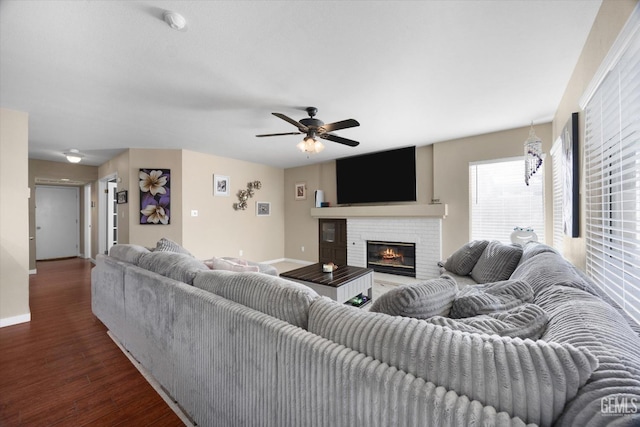 living room featuring dark wood-type flooring, ceiling fan, and a brick fireplace