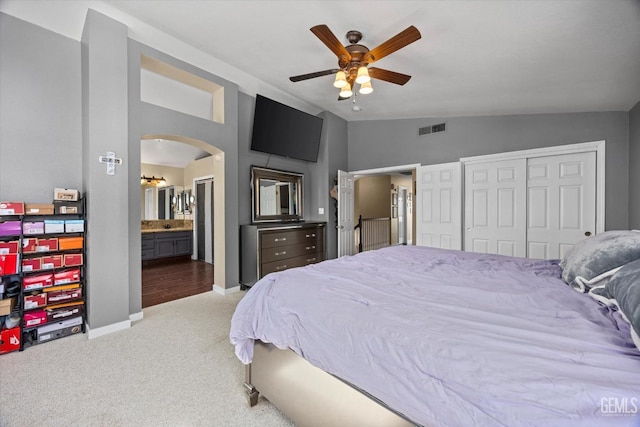 carpeted bedroom featuring ceiling fan, connected bathroom, vaulted ceiling, and a closet