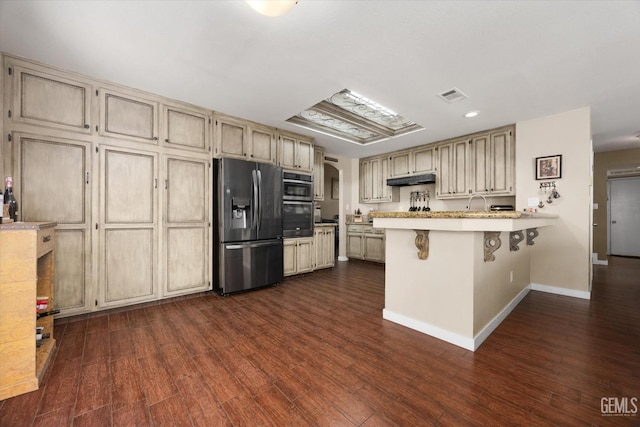 kitchen featuring a breakfast bar, dark hardwood / wood-style flooring, kitchen peninsula, stainless steel refrigerator with ice dispenser, and cream cabinets