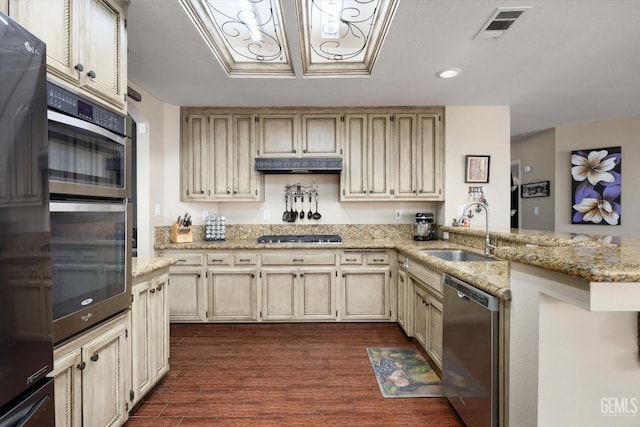 kitchen with cream cabinetry, sink, kitchen peninsula, and appliances with stainless steel finishes