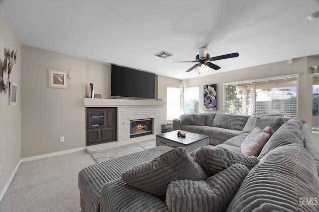 carpeted living room featuring a brick fireplace and ceiling fan