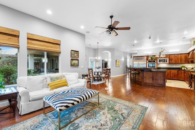 living room featuring wood-type flooring, sink, and ceiling fan with notable chandelier