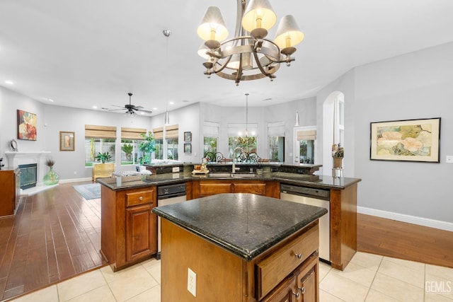 kitchen with sink, dishwasher, a spacious island, decorative light fixtures, and dark stone counters