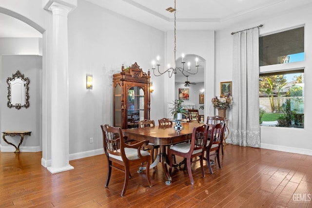 dining area with decorative columns, ceiling fan, a towering ceiling, and dark hardwood / wood-style flooring