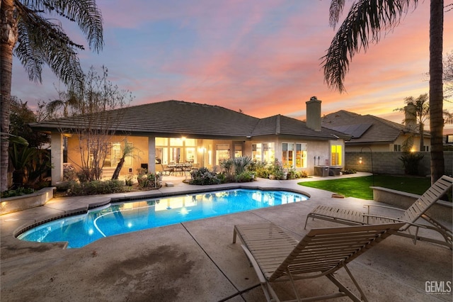 pool at dusk with a patio area