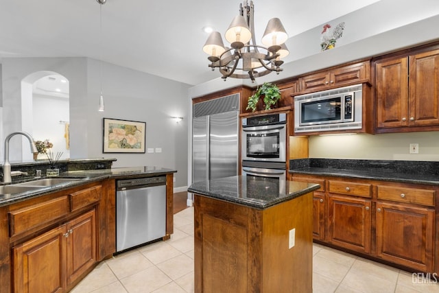 kitchen featuring sink, light tile patterned floors, hanging light fixtures, built in appliances, and a kitchen island