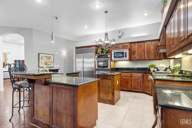 kitchen featuring sink, built in appliances, a chandelier, a kitchen island, and pendant lighting