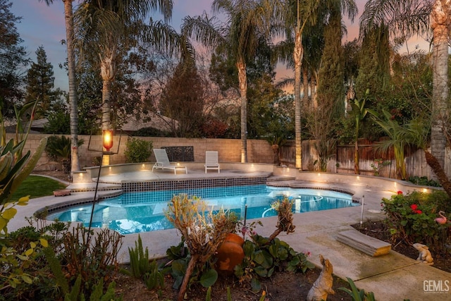 pool at dusk with a patio area