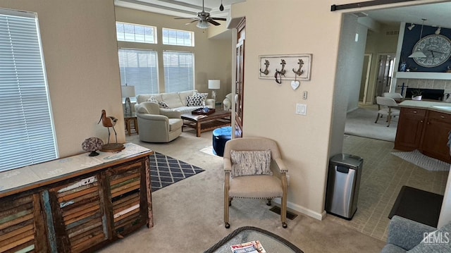 living room with ceiling fan, light colored carpet, and a fireplace