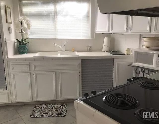 24551 Pueblo Ct, Tehachapi, CA 93561 - kitchen featuring exhaust hood, tile counters, white microwave, white cabinets, and range