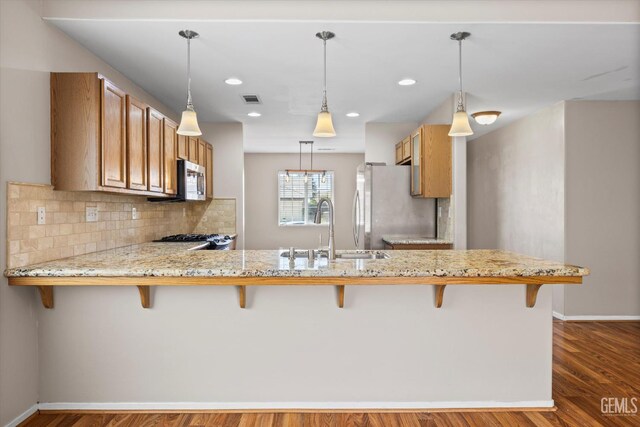11602 Trabancos Dr, Bakersfield, CA 93311 - kitchen featuring stainless steel appliances, a peninsula, dark wood-style floors, light stone countertops, and tasteful backsplash