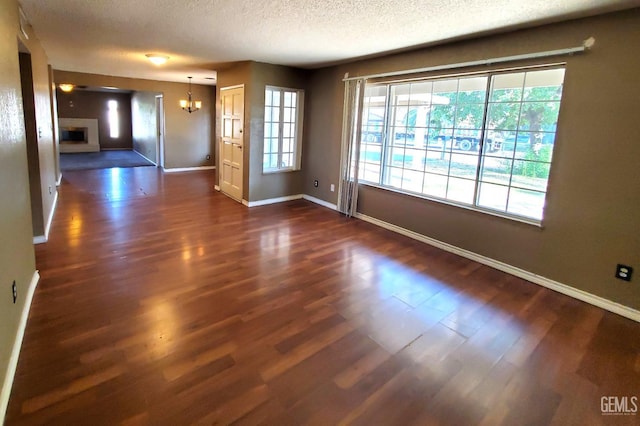 4204 Tyndall Ave, Bakersfield, CA 93313 - spare room featuring a chandelier, dark wood-style flooring, a textured ceiling, and a fireplace
