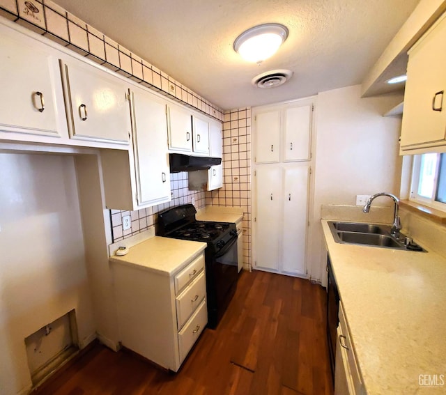4204 Tyndall Ave, Bakersfield, CA 93313 - kitchen with black gas range, under cabinet range hood, light countertops, white cabinetry, and dark wood-type flooring