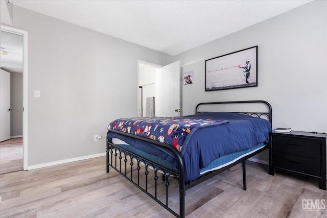 bedroom with a textured ceiling, baseboards, and wood finished floors