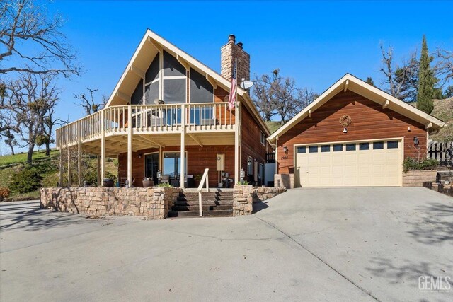 view of front of home with a garage, concrete driveway, a chimney, and an outbuilding