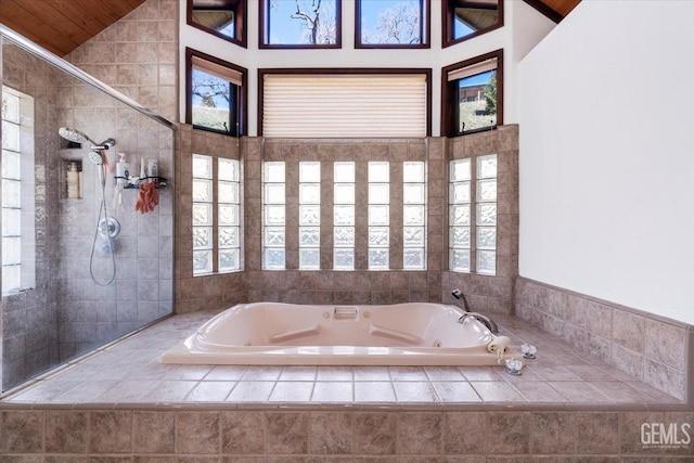 bathroom featuring a whirlpool tub, a tile shower, and lofted ceiling