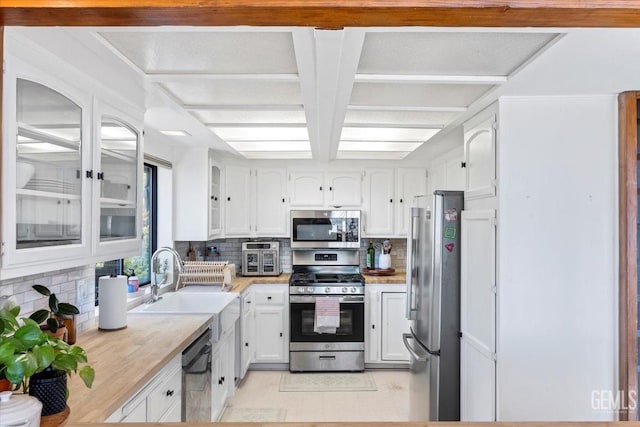 kitchen with tasteful backsplash, appliances with stainless steel finishes, light countertops, white cabinetry, and a sink