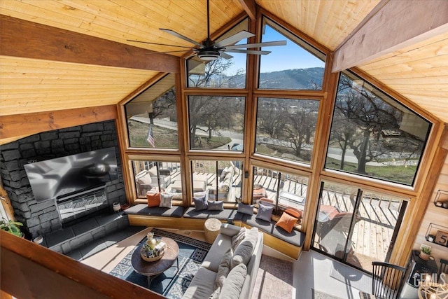 living area featuring a glass covered fireplace, wooden ceiling, beamed ceiling, expansive windows, and high vaulted ceiling