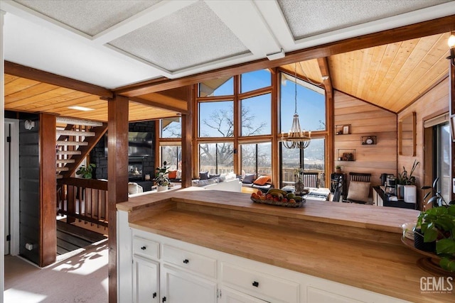 kitchen featuring lofted ceiling, wood walls, wood counters, and white cabinets