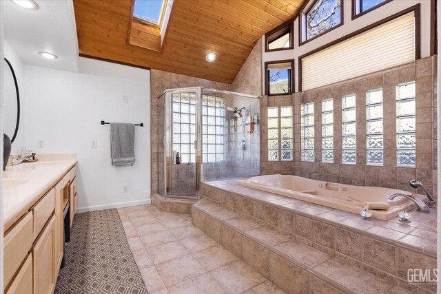 full bathroom with double vanity, vaulted ceiling with skylight, wood ceiling, a garden tub, and a shower stall