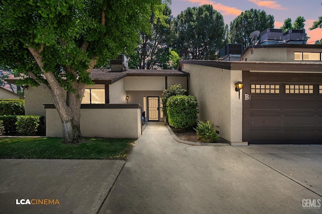 view of front facade featuring concrete driveway, stucco siding, and fence private yard