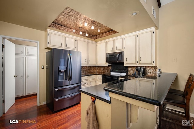 kitchen with dark wood finished floors, refrigerator with ice dispenser, black microwave, a peninsula, and electric stove