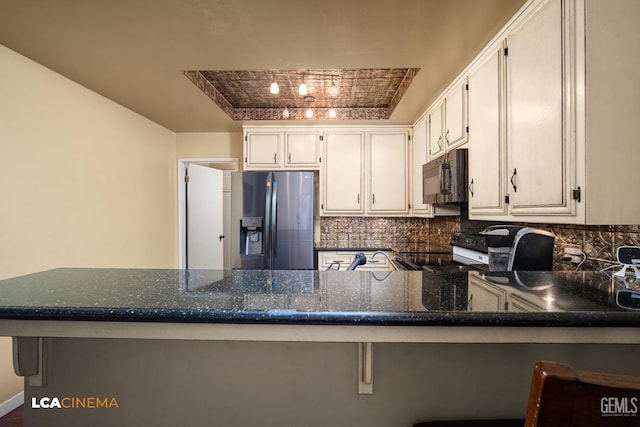kitchen featuring a peninsula, dark stone countertops, stainless steel refrigerator with ice dispenser, black microwave, and electric stove