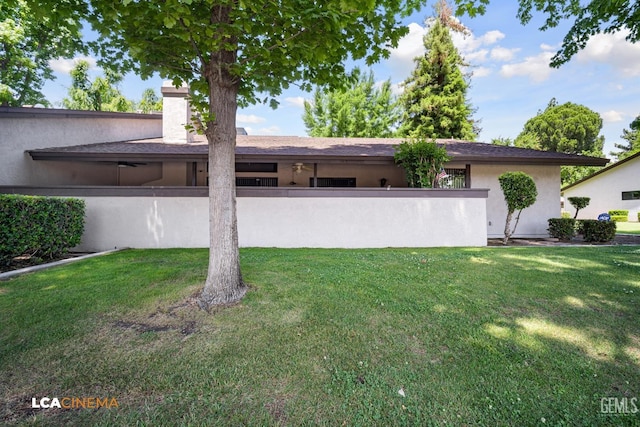 view of front of property featuring stucco siding, fence, and a front lawn