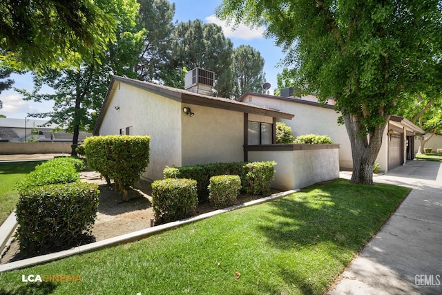 view of side of home featuring a yard, driveway, stucco siding, and a garage