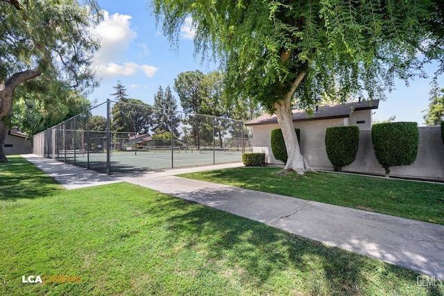 view of community with a yard, fence, and a tennis court