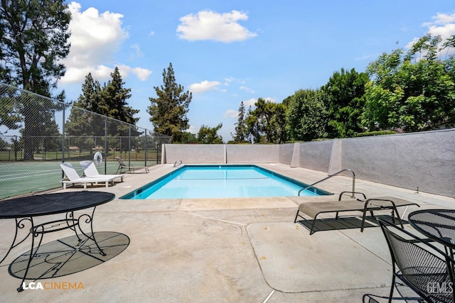 community pool with a patio and fence