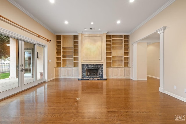 unfurnished living room with french doors, ornate columns, ornamental molding, a high end fireplace, and hardwood / wood-style floors