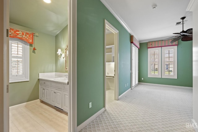 hallway with ornamental molding, sink, and light carpet